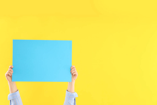 Female hands holding blank banner on yellow background - Foto, immagini