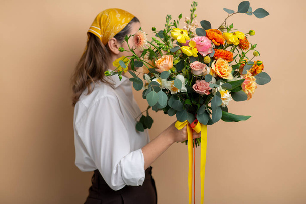 woman holding bunch of flowers on beige background - 写真・画像