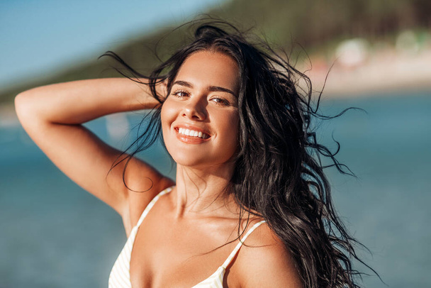 smiling young woman in bikini swimsuit on beach - Фото, изображение