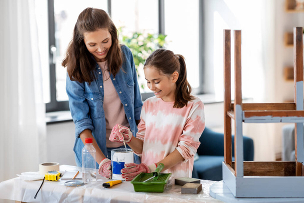 mother and daughter stirring grey paint at home - Foto, Bild