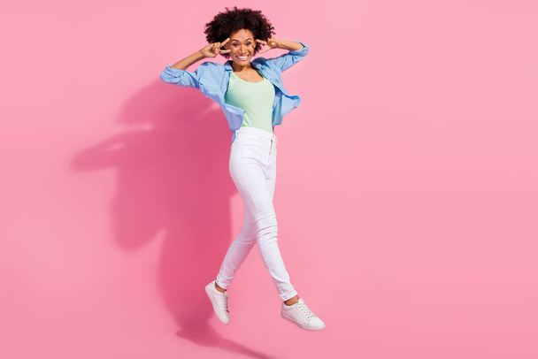 Photo of nice funky pretty lady jump show v-sign run wear denim shirt pants sneakers isolated pink color background - Foto, Imagen