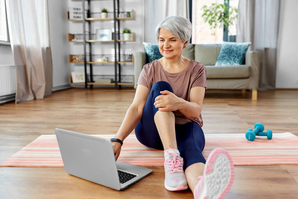 happy woman with laptop exercising at home - Foto, imagen