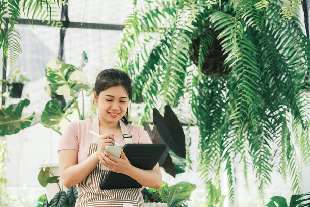 Young woman plant shop owner is checking customer order from website - Photo, Image