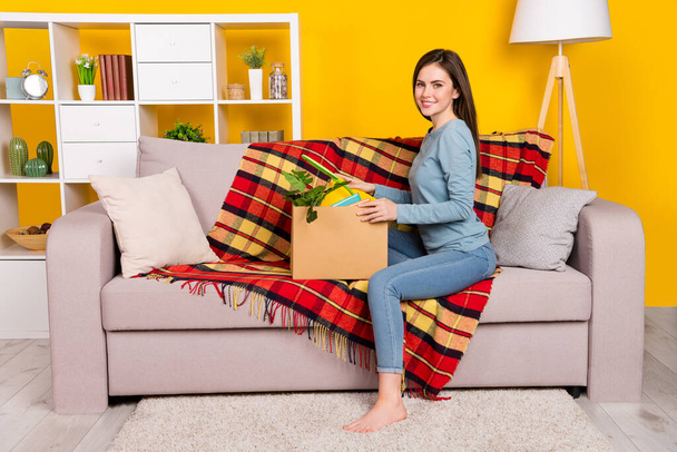 Full size profile photo of positive lady sitting couch carton box stuff isolated on yellow color background - Photo, image