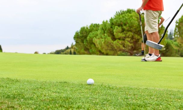 Golfozó a zöldön egy golfütővel a kezében. A játékos a zöld értékeli a lejtők és a távolság a lyuk, mielőtt célja a labdát felé a zászló. - Fotó, kép