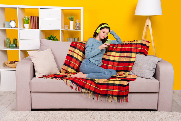Full size photo of positive peaceful lady sit barefoot couch use telephone isolated on yellow color background - Foto, Imagem
