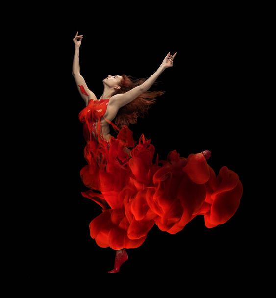 Firebird. Portrait of young tender woman covered with red paint and dye splah dancing isolated over black background - Photo, image