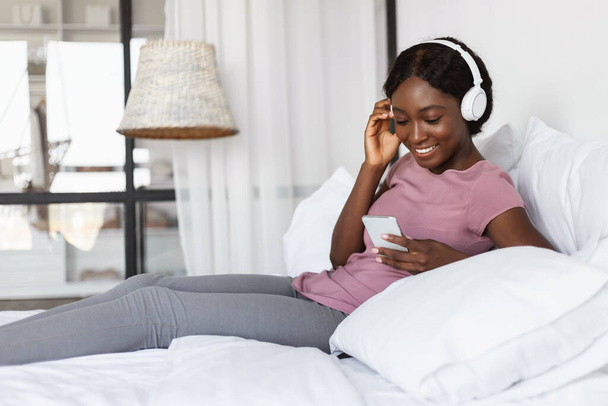 Siyah Kadın Akıllı Telefon Kullanıyor Evde Kulaklık Takan Müzik Dinliyor - Fotoğraf, Görsel