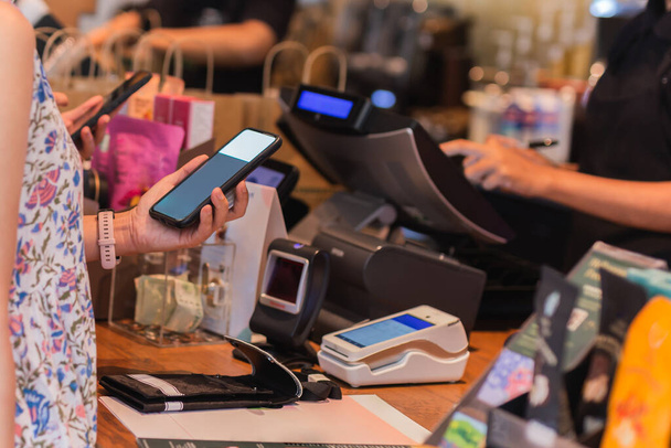 Femme payer sa facture via smartphone en utilisant la technologie NFC dans un restaurant. - Photo, image
