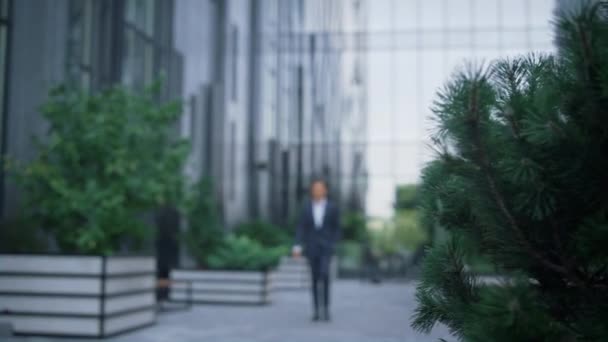 Vonzó üzletember sétál a belvárosban egyedül. Modern üveg irodaház - Felvétel, videó