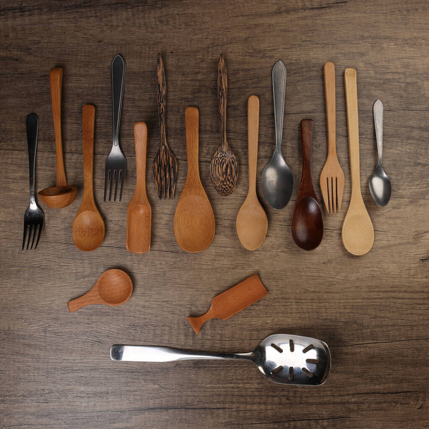 Różnorodność drewnianej metalowej łyżki plastikowej naczynia kuchenne na rustykalnym drewnie tło kopia przestrzeń tekstowa - Zdjęcie, obraz
