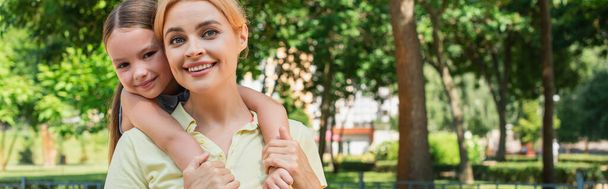 smiling girl embracing cheerful mother while looking at camera outdoors, banner - Foto, Bild