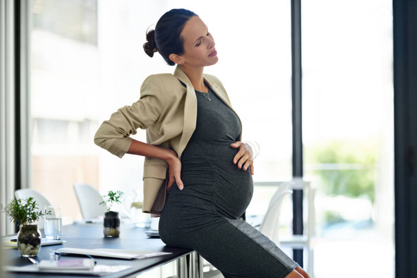 Third trimester aches. Shot of a pregnant businesswoman in discomfort in her office. - Фото, зображення