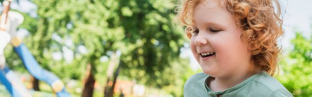 portrait of redhead boy with curly hair smiling outdoors, banner - Photo, Image