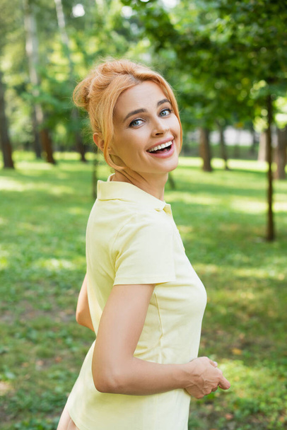 excited redhead woman looking at camera in summer park - Zdjęcie, obraz
