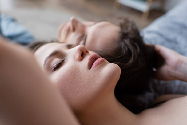 close up view of young woman with closed eyes lying near boyfriend  - 写真・画像