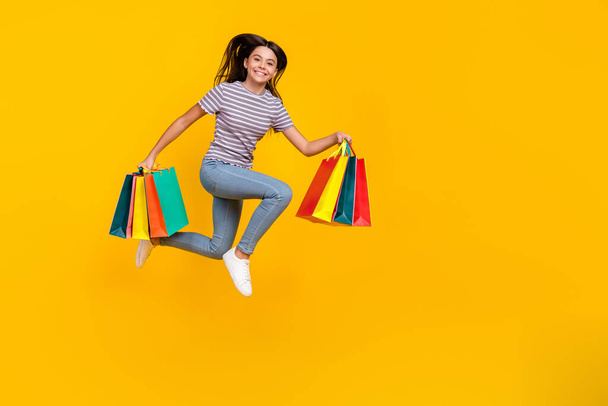 Full body profile side photo of young girl hold shopping bag run hurry isolated over yellow color background - Fotografie, Obrázek