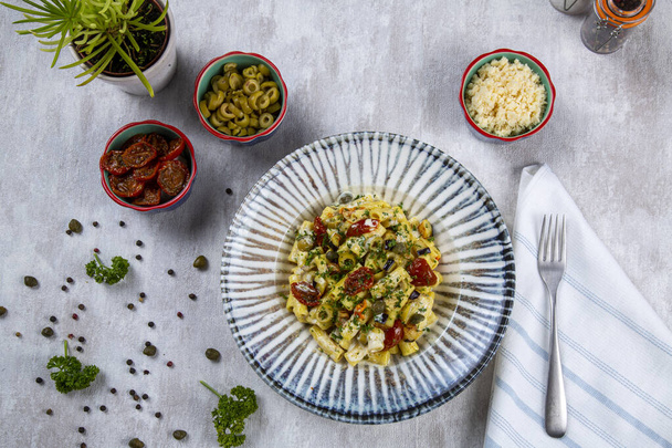 Italiaanse pasta met bechamelsaus en groenten. Veganistische pasta van gedroogde tomaten, broccoli, groene olijven en kwark - Foto, afbeelding