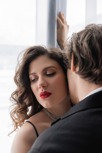 hombre de traje seduciendo a mujer rizada joven con labios rojos  - Foto, Imagen