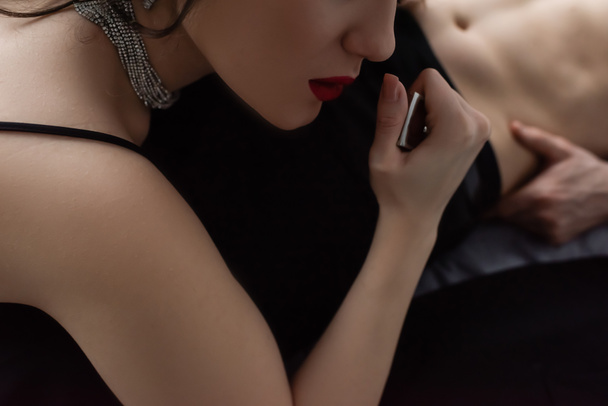 cropped view of sexy woman with red lips pulling belt of boyfriend  - Fotografie, Obrázek
