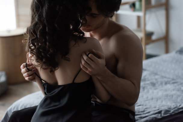shirtless man undressing curly woman in slip dress - Фото, зображення