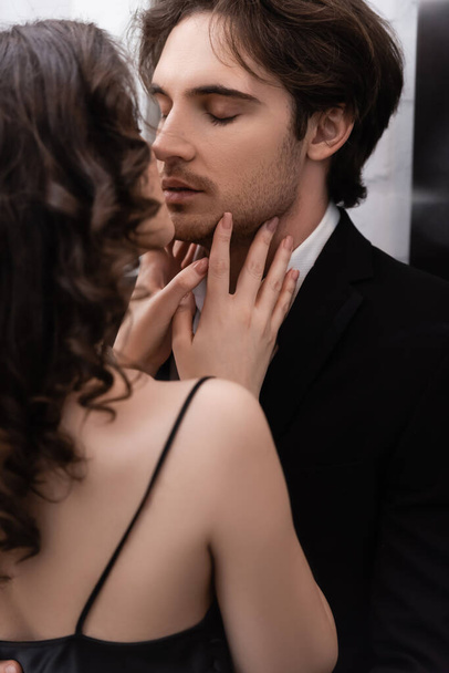 curly young woman kissing man in blazer  - Fotó, kép
