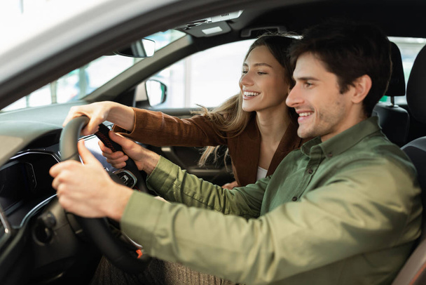 Feliz joven pareja prueba de conducción de coche nuevo en el concesionario de automóviles modernos - Foto, imagen