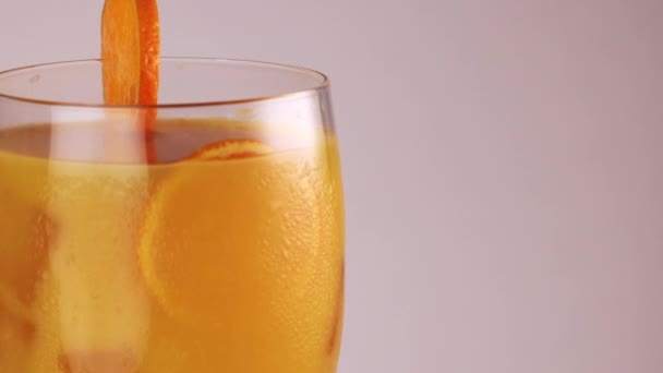 closeup preenchimento de vidro rotativo com suco de laranja gelo cubo geada na fatia de vidro de laranja na borda - Filmagem, Vídeo