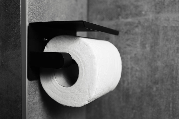 Λεπτομέρεια μπάνιο από μαύρο τοίχο στερεωμένο χαρτί τουαλέτας. Μαύρο και άσπρο. - Φωτογραφία, εικόνα