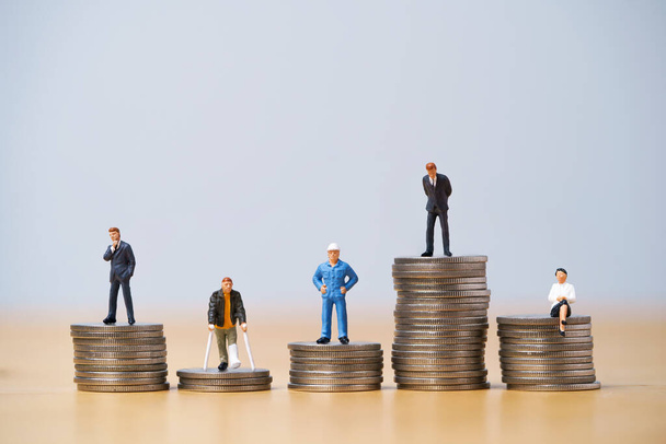 Cinque figure in miniatura in ogni carriera in piedi per diverse monete alte e basse accatastamento per variazione di reddito o salario in ogni concetto di lavoro. - Foto, immagini