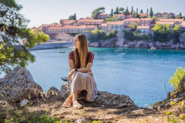 Woman tourist on background of beautiful view of the island of St. Stephen, Sveti Stefan on the Budva Riviera, Budva, Montenegro. Travel to Montenegro concept - Foto, afbeelding