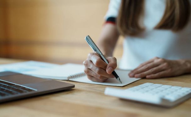 Detailní záběr ženských rukou s notebookem a perem psaní poznámek při výpočtu s kalkulačkami doma - Fotografie, Obrázek