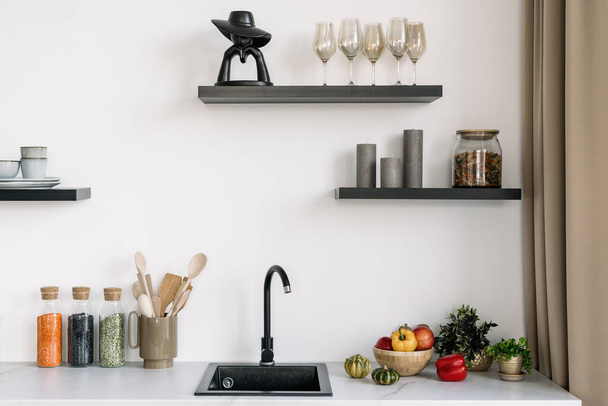 Skandináv konyha belsőépítészet fehér tónusú fekete mosogatóval. Főzőhely. Konyhai és élelmiszeripari termékek. Házi dekoráció és edények - Fotó, kép
