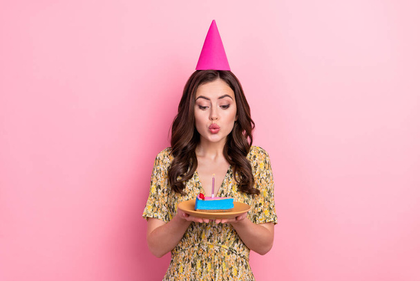Foto di divertente signora tenere pezzo torta soffiare candela respiro isolato su sfondo di colore rosa - Foto, immagini