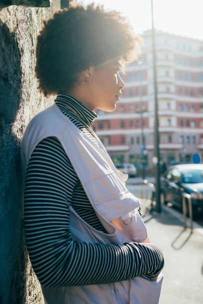 Young pensive mixed race curly hair woman posing outdoor city backlight overlooking thoughtful - Photo, image