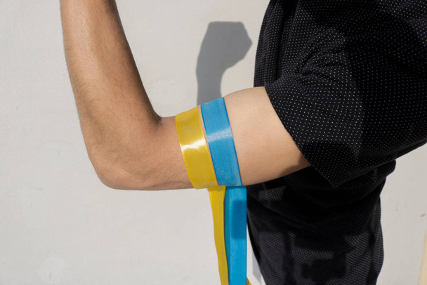 Solidaridad con Ucrania. Bandera de Ucrania cinta de color atada en el brazo. - Foto, Imagen