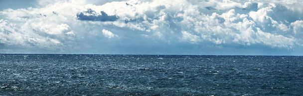 Panoramic view of Baltic sea from sandy shore (sand dunes) during the storm. Dramatic sky with dark cumulus clouds. Waves, water splashes. Seascape. Weather, climate change, nature - Photo, Image