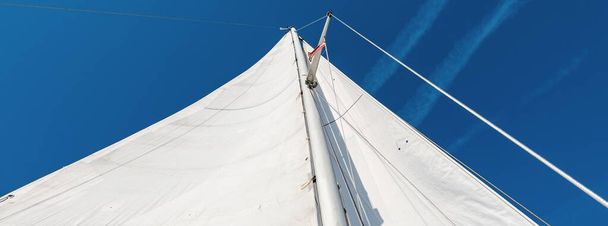 Witte zeilen van een sloep opgetuigd jacht tegen helderblauwe lucht. Vervoer, nautisch schip, zeilen, sport, recreatie - Foto, afbeelding
