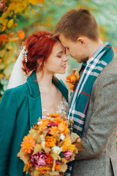Egy fiatal pár portréja az esküvői boltív közelében. A vörös hajú lány és a jóképű srác ölelik egymást.. - Fotó, kép