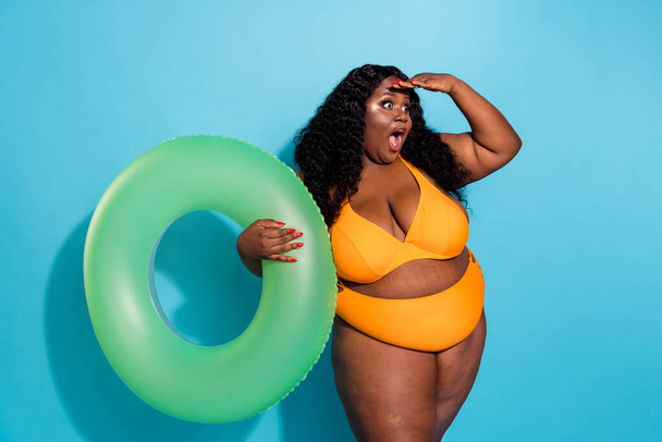 Photo of shocked chubby body confident lady hold rubber ring see empty space season bargain isolated over blue color background - Фото, зображення