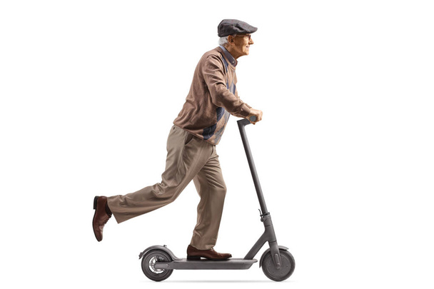 Full length profile shot of a an elderly male riding an electric scooter isolated on white background - Zdjęcie, obraz