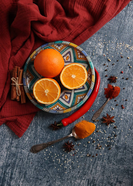 Oranges, poivron rouge, poudre de paprika, curcuma et anis vue de dessus photo. Des épices sur une table. Préparation de repas épicés en cours. Nature morte colorée avec des fruits.  - Photo, image