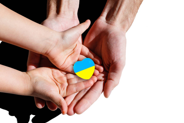 Des mains de famille tenant un cœur aux couleurs ucraines. Paix et pas de concept de guerre. - Photo, image