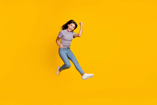 Full size photo of young lady rejoice success fists hands triumph jump isolated over yellow color background - Foto, Imagen