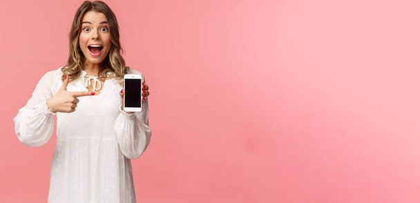 Porträt einer beeindruckten, aufgeregten jungen blonden Frau, die etwas Tolles zeigt, den Handybildschirm zeigt und erstaunt lächelt, prahlt mit ihrem jüngsten Match auf Dating-App - Foto, Bild