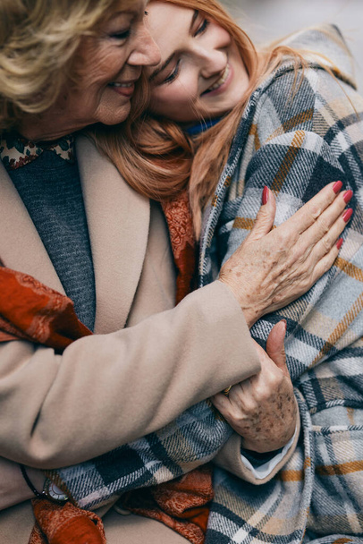 Una abuela y una nieta felices abrazos fuera. - Foto, Imagen
