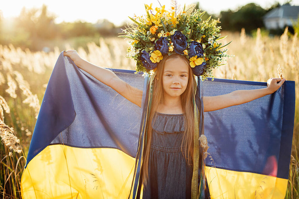 Girl carries fluttering blue and yellow flag of Ukraine in field. - Foto, afbeelding