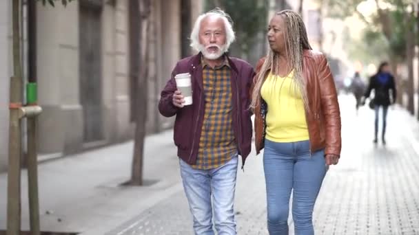 starší páry procházející se po městě, asijský muž a Afroameričanka, cestují důchodci. - milovat seniory - - Záběry, video