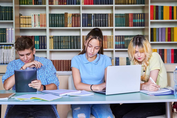 Group of teenage students studying in school library. - Fotó, kép