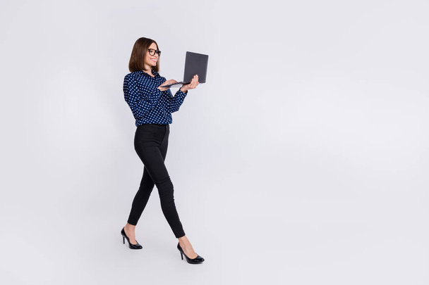 Fénykép bájos hölgy séta hold netbook típusú e-mail kopás pontozott blúz stilettos elszigetelt szürke színű háttér - Fotó, kép